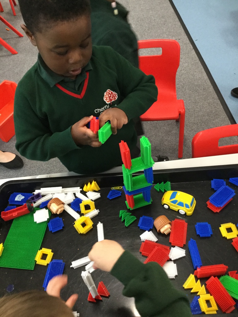 A young boy playing with blocks on a table in a classroom.